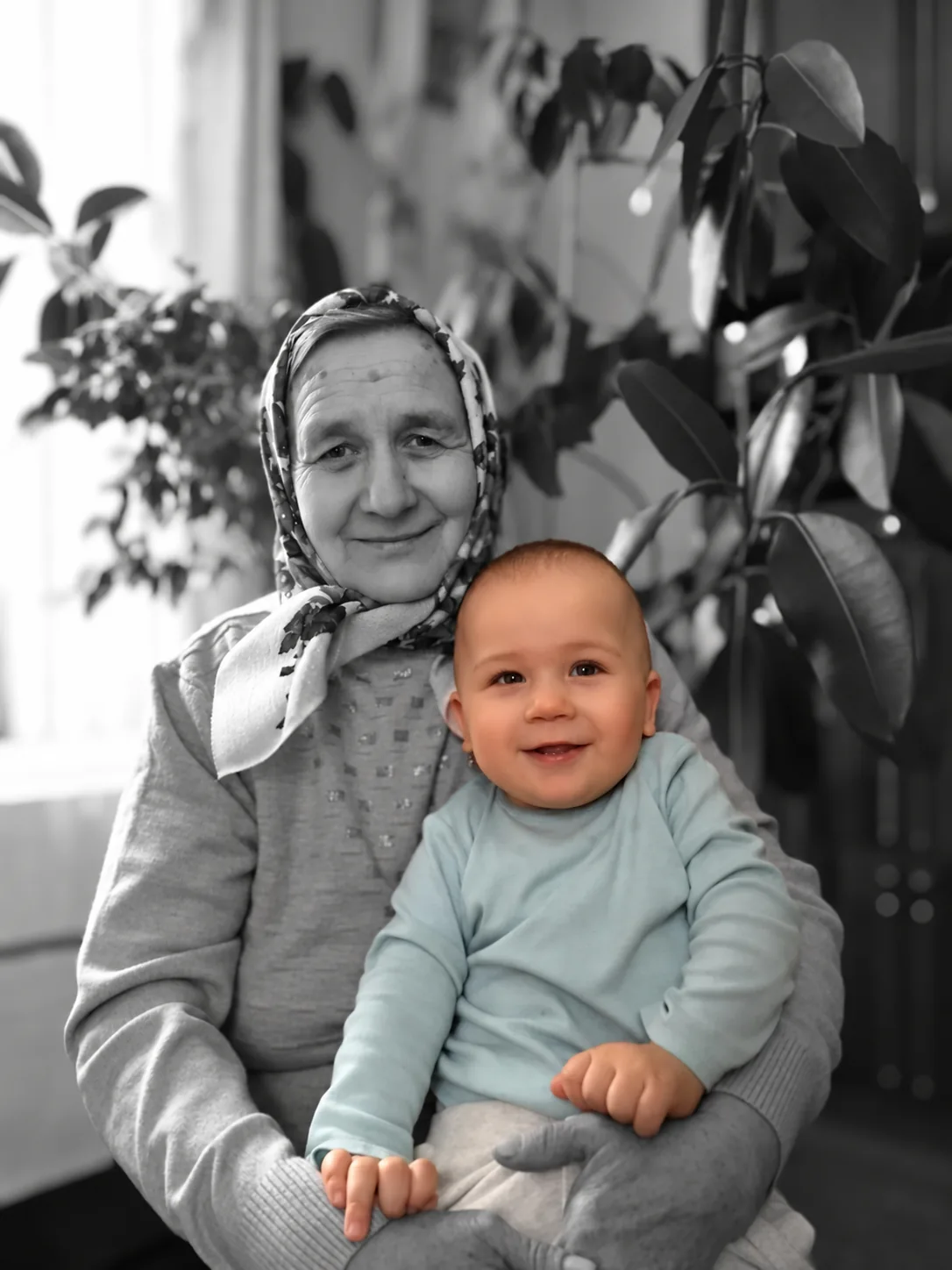 Babcia z małym dzieckiem na kolanach; dziecko zachowuje kolor na czarno-białym tle
